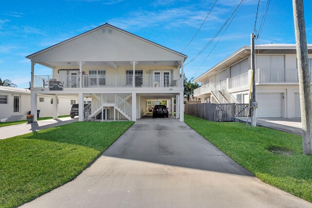 raised beach house featuring a front yard, a carport, and covered porch