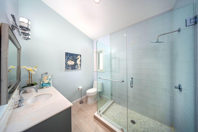 bathroom with a shower with door, hardwood / wood-style floors, vanity, vaulted ceiling, and toilet