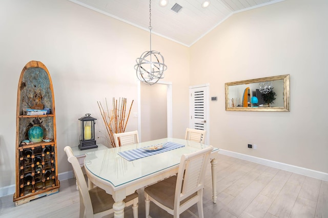 dining room featuring light hardwood / wood-style flooring, vaulted ceiling, ornamental molding, and an inviting chandelier