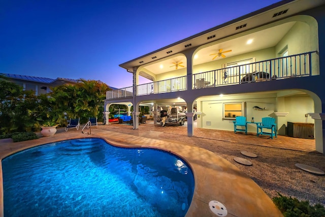 pool at dusk with ceiling fan and a patio