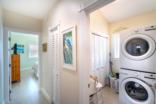 laundry area with stacked washer / dryer and light hardwood / wood-style floors