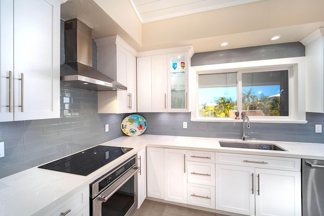 kitchen with stainless steel appliances, white cabinetry, sink, and wall chimney exhaust hood