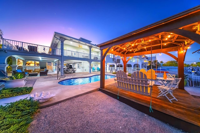 pool at dusk with a gazebo and a patio area