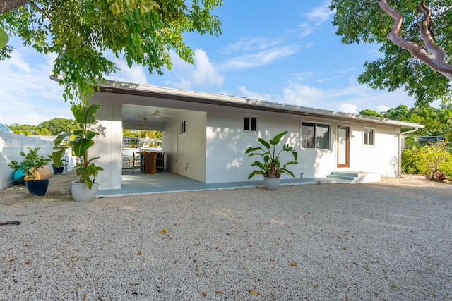 back of property with ceiling fan and a patio