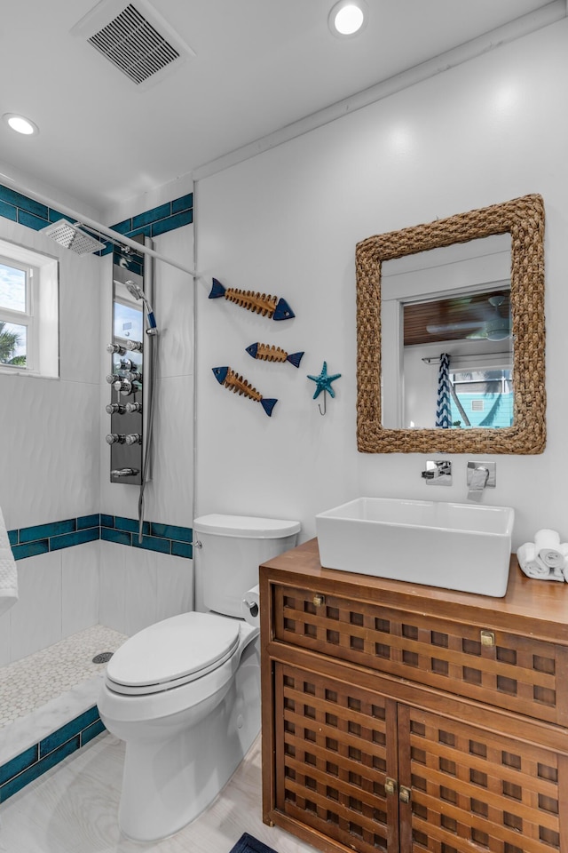 bathroom with vanity, toilet, and a tile shower