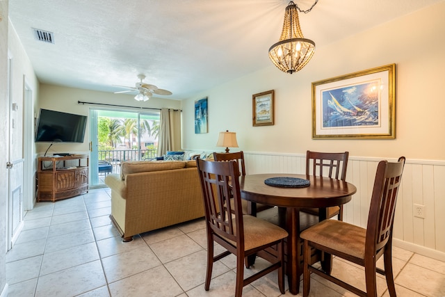 dining area featuring ceiling fan with notable chandelier, light tile patterned floors, and a textured ceiling