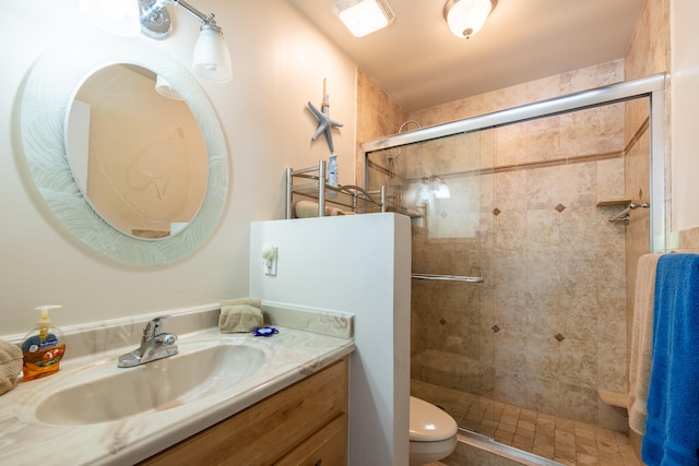 bathroom with an enclosed shower, vanity, and toilet