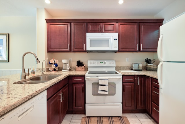 kitchen with white appliances, light stone countertops, sink, and light tile patterned floors