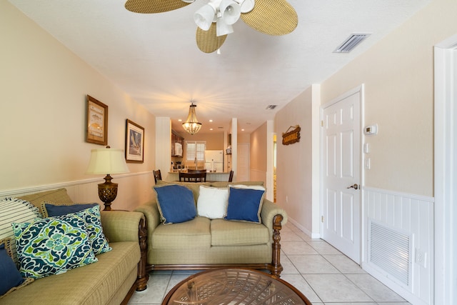 tiled living room featuring ceiling fan with notable chandelier