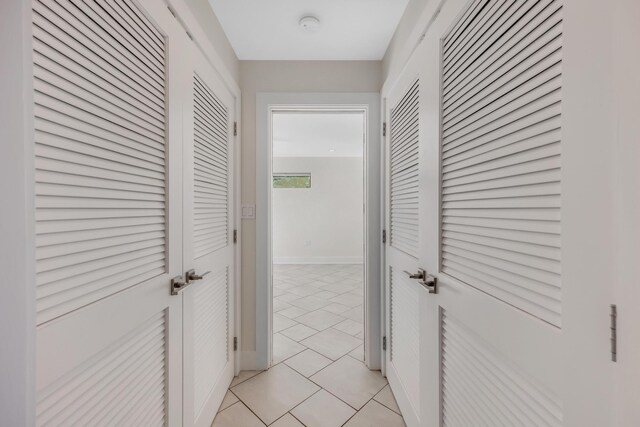 corridor featuring baseboards and light tile patterned floors