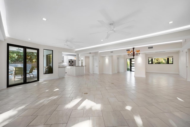 unfurnished living room featuring plenty of natural light, ceiling fan with notable chandelier, and light tile patterned floors