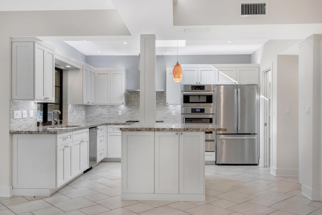 kitchen featuring light stone countertops, appliances with stainless steel finishes, a sink, decorative backsplash, and visible vents