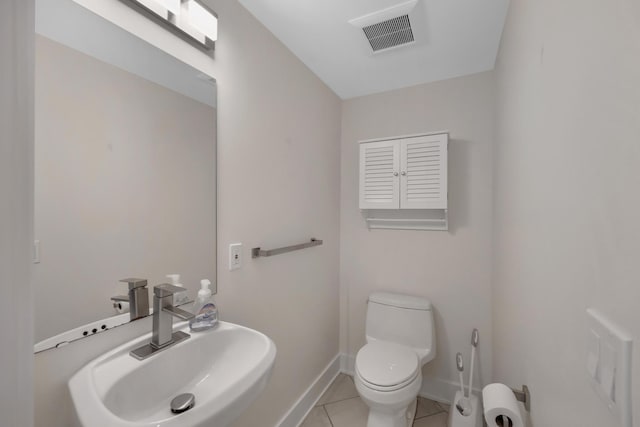 half bathroom featuring visible vents, a sink, tile patterned floors, baseboards, and toilet
