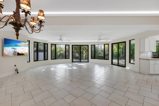 unfurnished living room featuring plenty of natural light, light tile patterned flooring, and a notable chandelier