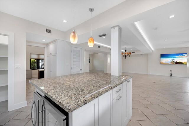 kitchen featuring light stone counters, a chandelier, open floor plan, and visible vents
