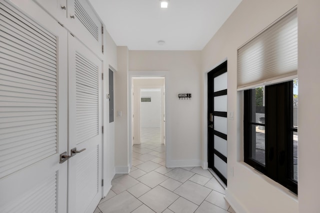 corridor featuring baseboards, light tile patterned flooring, and visible vents