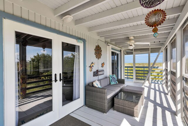 sunroom with a ceiling fan and beam ceiling