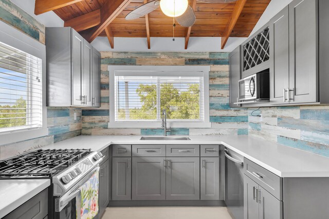 kitchen with appliances with stainless steel finishes, light countertops, a sink, and gray cabinetry