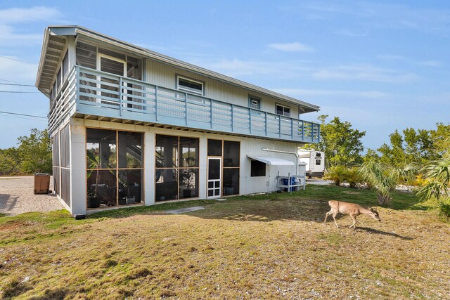 rear view of property featuring a sunroom and a lawn