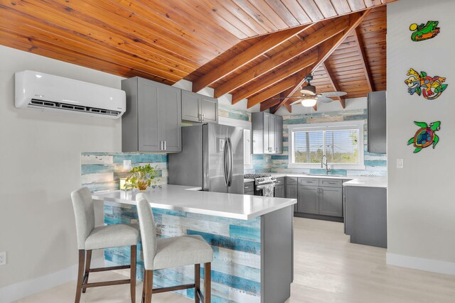 kitchen with a breakfast bar area, stainless steel appliances, gray cabinets, light countertops, and a peninsula