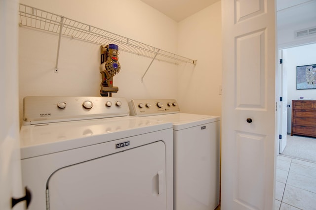 clothes washing area with light tile patterned floors and washer and clothes dryer