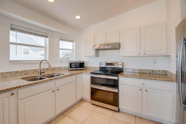 kitchen with sink, white cabinetry, vaulted ceiling, appliances with stainless steel finishes, and light stone countertops