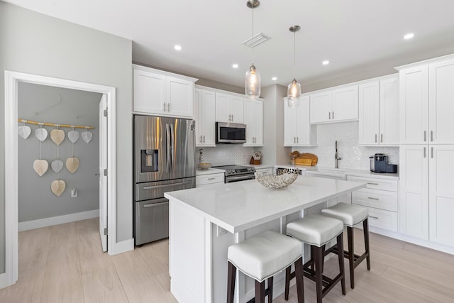 kitchen with hanging light fixtures, a center island, white cabinets, and appliances with stainless steel finishes