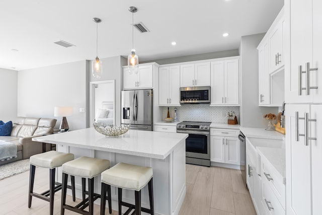 kitchen with a kitchen island, white cabinetry, appliances with stainless steel finishes, and a breakfast bar area