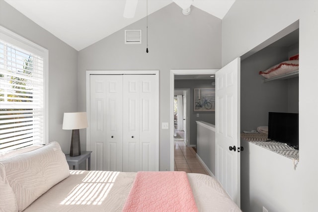 bedroom with tile patterned flooring, visible vents, vaulted ceiling, and a closet