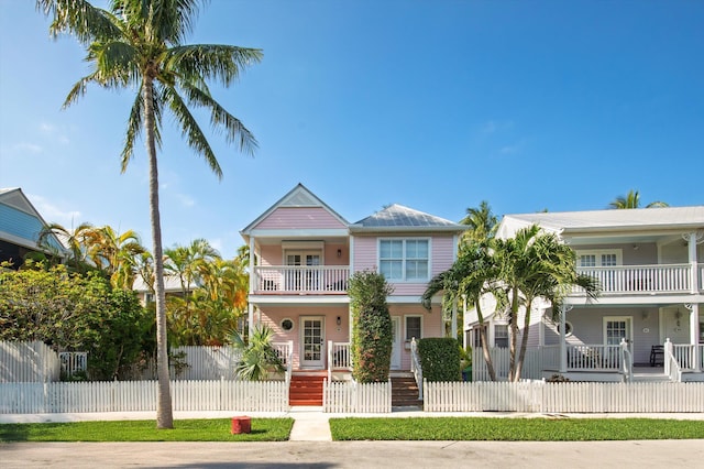 view of front of property featuring covered porch, a fenced front yard, and a balcony