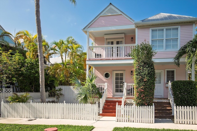 view of front facade featuring a balcony, metal roof, a fenced front yard, and a porch