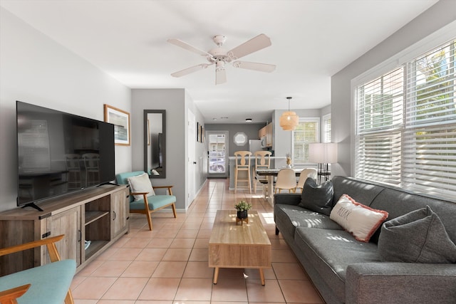 living area with a ceiling fan, light tile patterned flooring, and baseboards