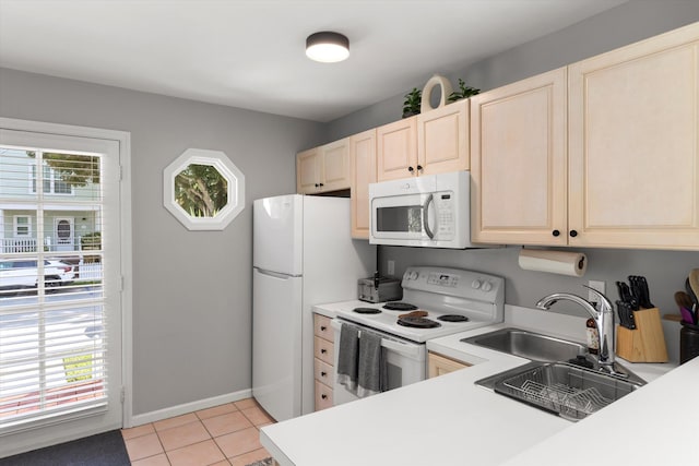 kitchen featuring light tile patterned floors, white appliances, a sink, baseboards, and light countertops