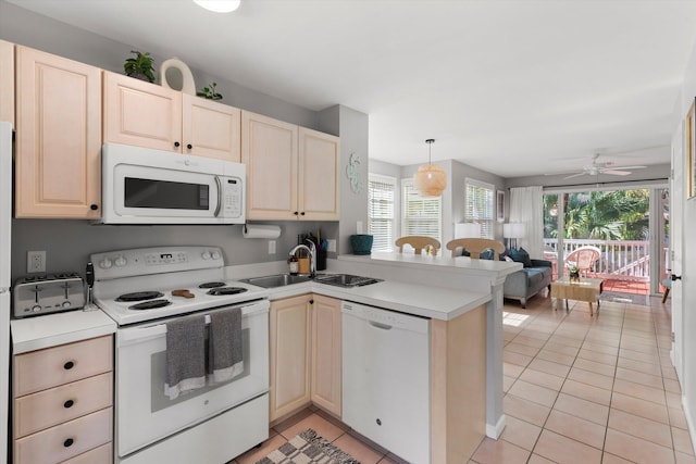 kitchen featuring white appliances, light tile patterned floors, open floor plan, a peninsula, and a sink