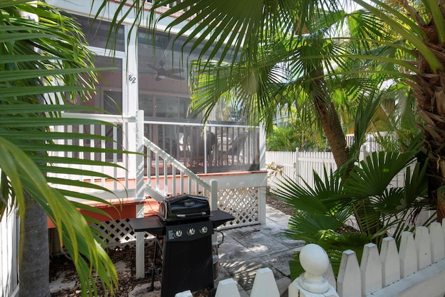 view of patio / terrace with a sunroom, a grill, and fence