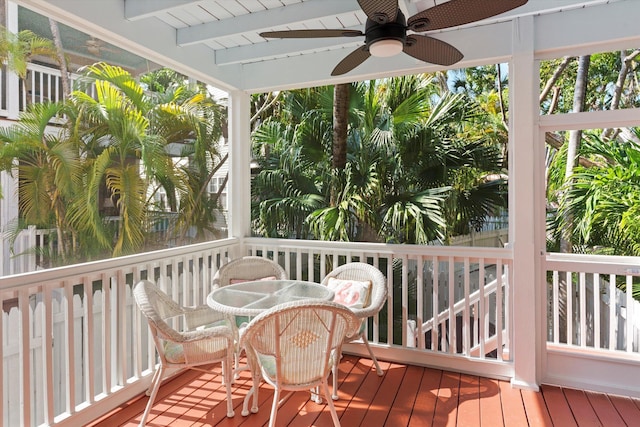 sunroom with beamed ceiling and a ceiling fan