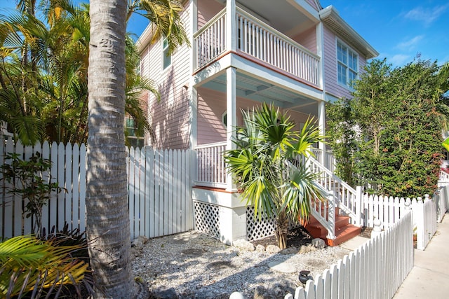 view of home's exterior with a balcony, covered porch, and fence