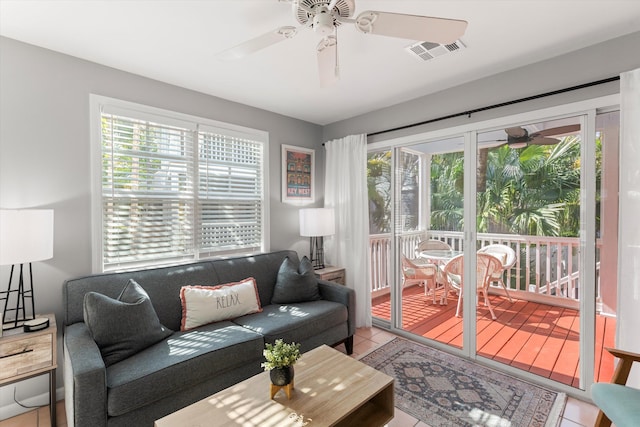 tiled living room with a sunroom, plenty of natural light, visible vents, and ceiling fan