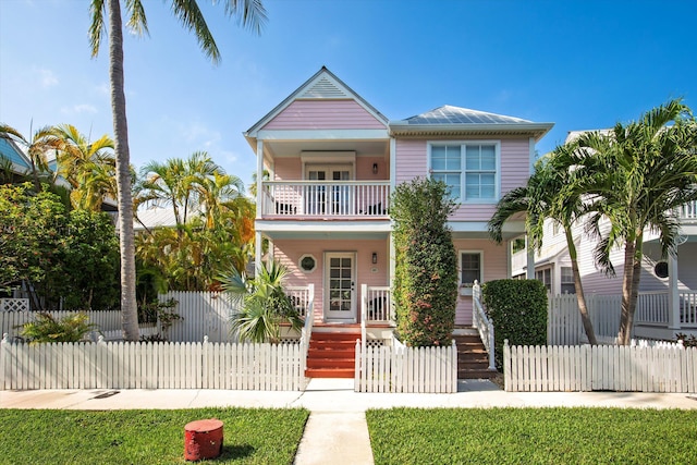 view of front of home featuring a balcony, covered porch, and a fenced front yard