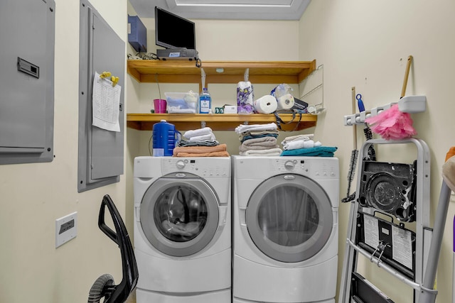 clothes washing area featuring laundry area, electric panel, and washer and clothes dryer