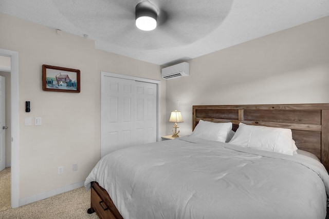 bedroom with carpet flooring, a wall unit AC, ceiling fan, a textured ceiling, and a closet