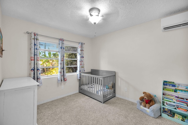 carpeted bedroom featuring a textured ceiling, a wall unit AC, and a crib