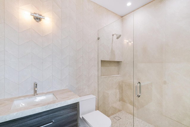 bathroom with tile walls, an enclosed shower, vanity, and toilet