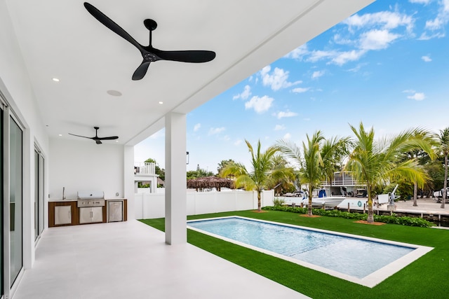 view of swimming pool with an outdoor kitchen, grilling area, a patio area, and a lawn