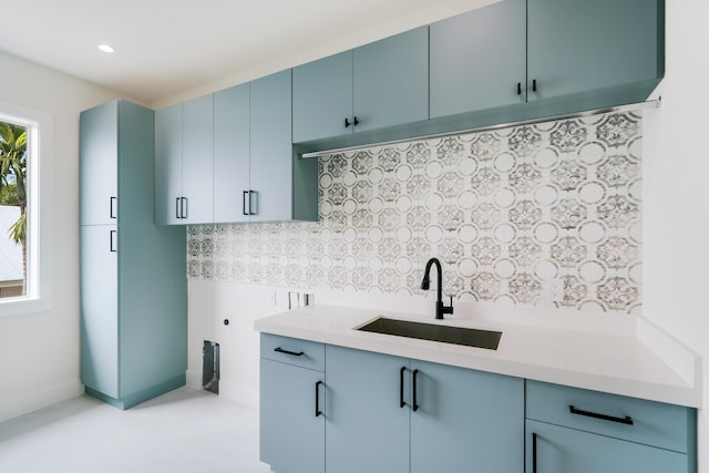 kitchen featuring blue cabinets, sink, and decorative backsplash