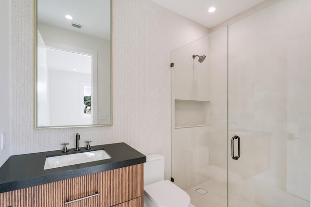 bathroom with vanity, toilet, and a shower with shower door