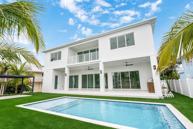 back of house featuring ceiling fan, a patio, a balcony, and a lawn