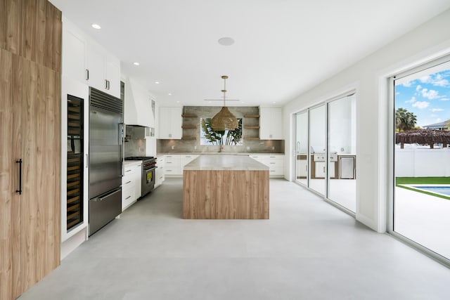 kitchen with white cabinetry, a center island, hanging light fixtures, high quality appliances, and custom range hood