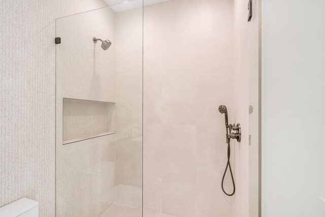 bathroom with tiled shower and toilet