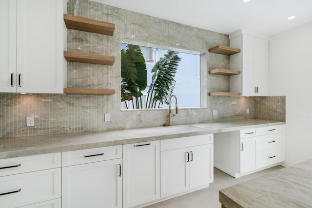 kitchen with sink, white cabinets, light stone counters, and decorative backsplash